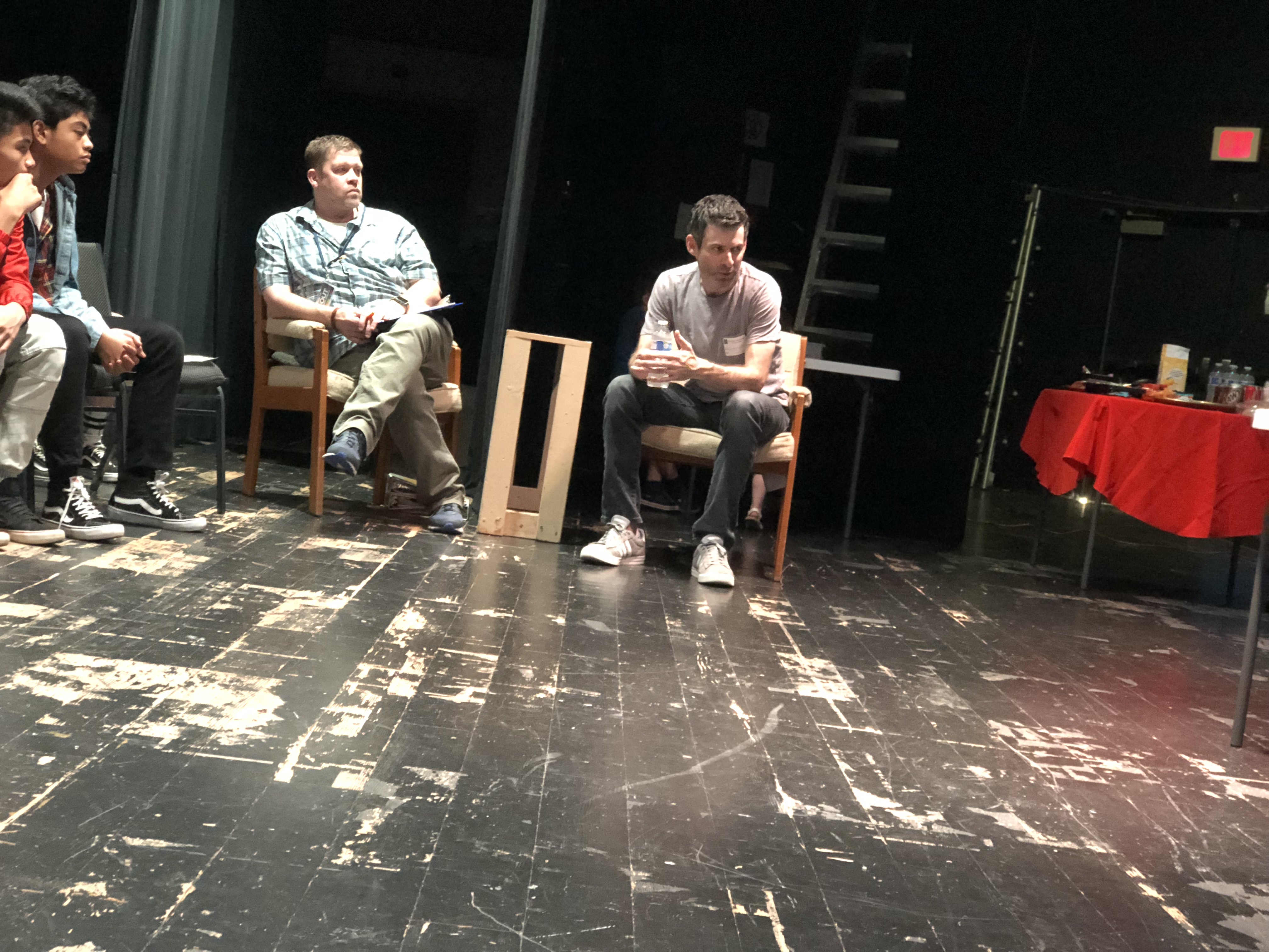 Jonathan seated onstage with other participants in a theater discussion